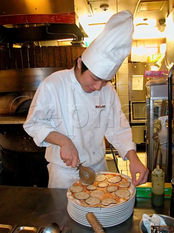 Chef cutting a cooked aubergine pizza in an Italian   style restaurant  Tokyo Japan