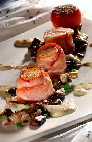 Chicken wrapped in bacon on mushrooms with sauce garnish