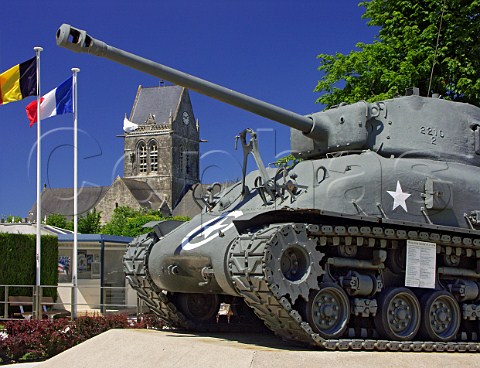 Sherman tank in the DDay museum with the dummy   paratrooper in honour of John Steel on the church   tower behind SteMreEglise Manche France    BasseNormandie