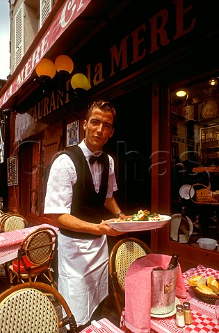 French waiter serving a lunch dish at the renowned  restaurant La Mere Catherine Montmartre Paris  France