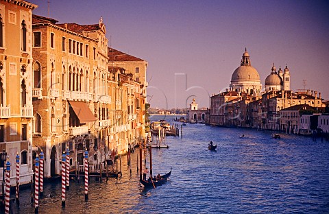 Grand Canal Venice with gondoliers and Basilica di Santa Maria della Salute in late afternoon sunshine Venice Italy