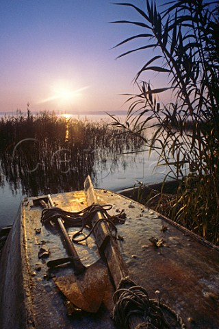 Lake Bolsena with upturned fishing boat and old   weathered farming implements at sunset Lazio Italy