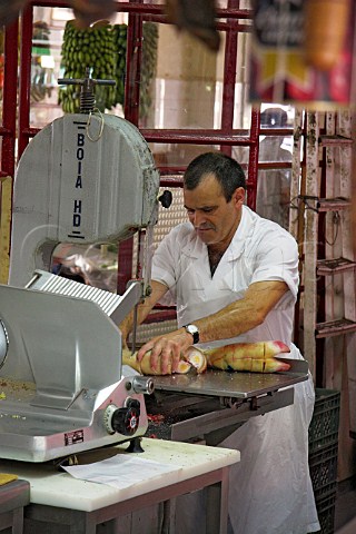 Cutting up pigs trotters in a butchers shop at the   Mercado dos Lavradores Funchal Madeira Portugal