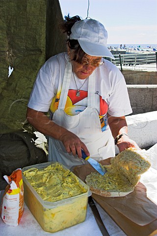 Buttering bread cakes with garlic butter during a  festival at Canial Madeira Portugal