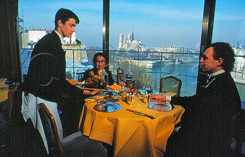 Waiter serving guests at   La Tour DArgent restaurant with view of Notre Dame Cathedral and river Seine   Paris France