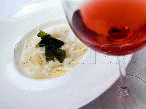 Ribbons of squid in coconut milk with seaweed  garnish and glass of rose wine