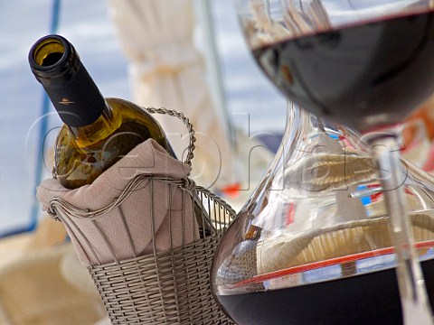 Red wine bottle in cradle with decanter and glass of   wine in outdoor restaurant situation