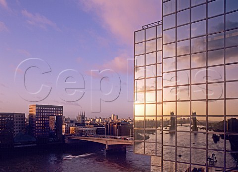 Dawn over London Bridge and River Thames with Tower   Bridge reflected in modern office glass windows   London UK