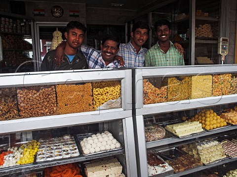 Indian men behind counter of shop selling sweets and   savouries Chennai Madras India