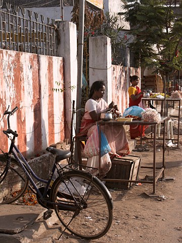 Indian women making flower garlands by the roadside   For wearing in hair during temple visits Chennai   Madras India