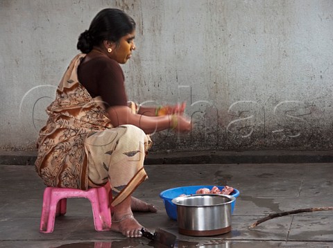 Indian woman using her toes to hold cleaver to cut   meat Chennai Madras India