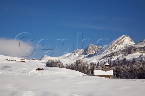 Skiers and snowboarders have lunch by the chapel on the Col des Annes below the Pointe dAreu 2478m in the Chaine des Aravis   Le GrandBornand HauteSavoie France