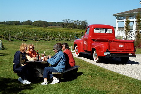 Visitors drinking wine with lunch by red pickup truck in car park of Bedell Cellars Cutchogue Long Island New York USA