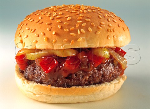 Beefburger with fried onion and red peppers in a toasted sesame seed bread roll