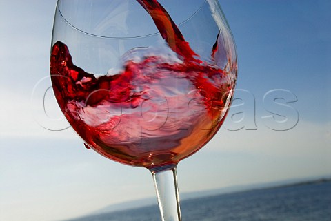 Red wine being poured into glass with seascape behind