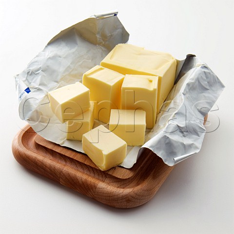 A block of butter partly cut into cubes on silver wrapper