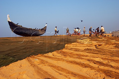 Fishermen busy with their nets laying them out to dry in the morning sunshine on the beach north of Thiruvananthapuram Trivandrum Kerala India
