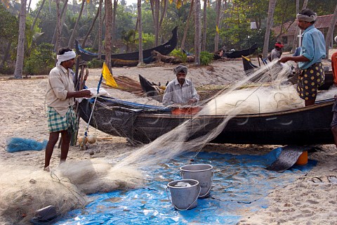 Fishermen sorting their nets on the palm fringed beach at the rustic fishing village of Kattoor Kalavoor Alappuzha Alleppey Kerala India