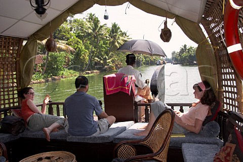 Tourists enjoying the relaxation of a houseboat cruising the Kuttanad the backwaters of Kerala known as the Venice of the East Kerala India