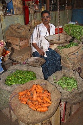 Man selling carrots chillies and green beans at Connemara Market Thiruvananthapuram Trivandrum Kerala India