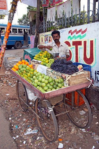Man selling fresh fruit from a mobile cart on a street corner in Thiruvananthapuram Trivandrum Kerala India