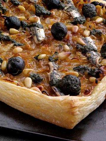 Pissaladire close up with black olives anchovies and pine nuts