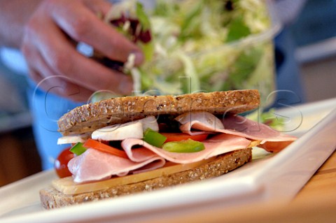 Making a Boterham a Dutch lunchtime sandwich Ham cheese green pepper tomato and mushroom on brown bread