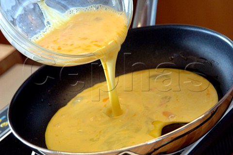 Pouring omelette mix into a frying pan