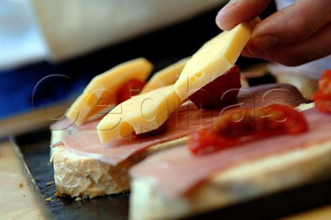 Putting ham cheese and tomato on slices of bread prior to grilling