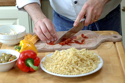 Chef preparing ingredients for a pasta salad