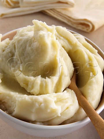 A bowl of mashed Maris Piper potato with a wooden spoon