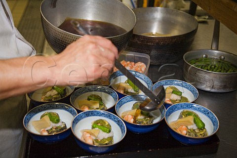 Preparing dishes of tempura soba with bamboo shoot and prawn in a Japanese restaurant