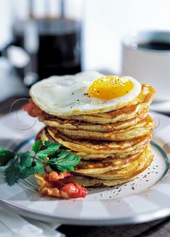 Stack of american pancakes with a fried egg on top
