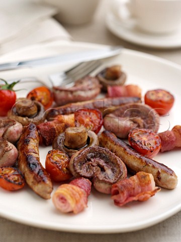 Mixed grill plate chipolata sausages kidneys mushrooms and grilled tomatoes in a table setting