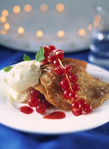 Plate of pancakes with red currants and cream