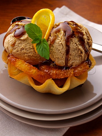 Caramel icecream and orange slices in a wafer  basket topped with toffee sauce