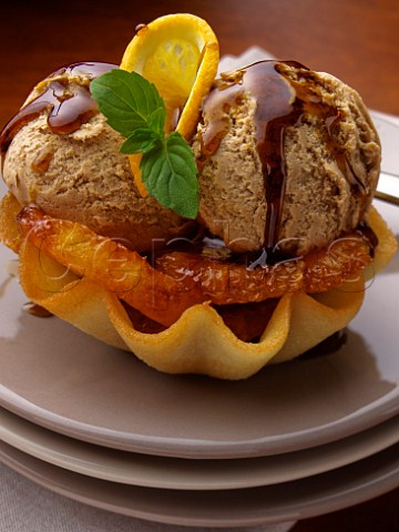 Caramel icecream and orange slices in a wafer  basket topped with toffee sauce