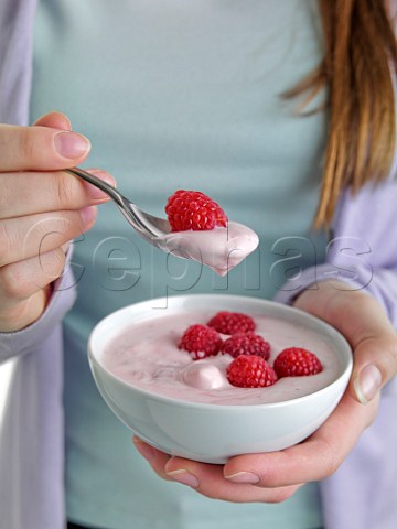 Woman eating raspberries and yoghurt