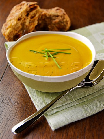 Bowl of pumpkin soup with brown bread rolls