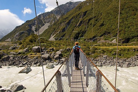 Walker on suspension bridge over Hooker River Mt CookAoraki National Park South Island New Zealand