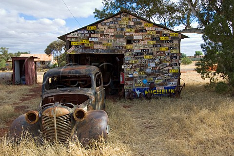 Rusty car and old number plates outside preserved miners cottages Gwalia  Western Australia