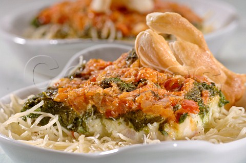 Spinach and tomato topped fish on a bed of spaghetti with lobster shaped pastry