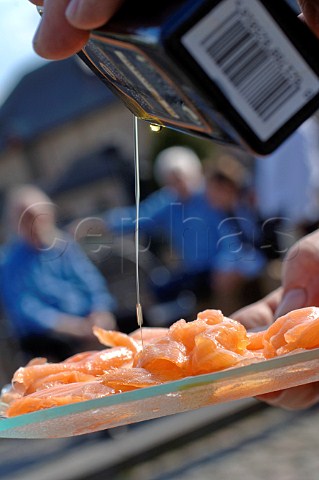 Drizzling olive oil on to smoked salmon slices