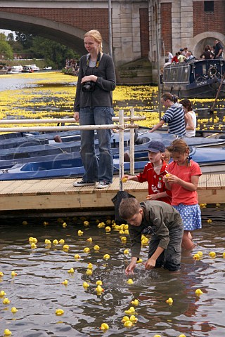 Children have fun as some of the 165000 plastic ducks gather near Hampton Court bridge on the River Thames during the Great British Duck Race 2007 a new Guinness World Record East Molesey Surrey England