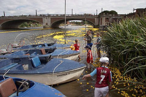 Children have fun as some of the 165000 plastic ducks get caught up around rowing boats near Hampton Court bridge on the River Thames during the Great British Duck Race 2007 a new Guinness World Record East Molesey Surrey England