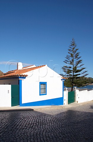 Traditional style house and cobbled road leading down to the Mira River estuary at Vila Nova de Milfontes Odemira Portugal