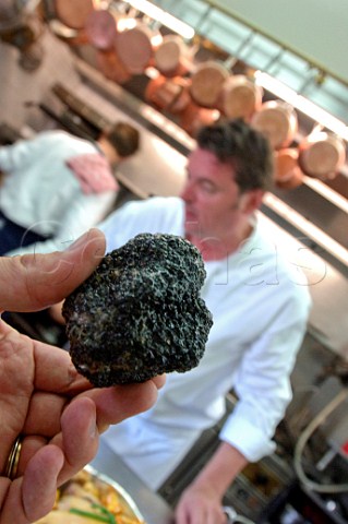 Hand holding a black truffle in a restaurant kitchen