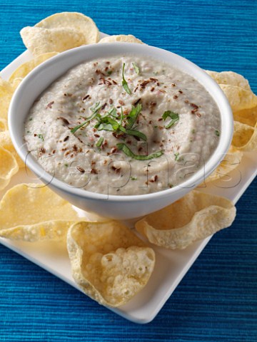Bowl of aubergine raita with mini poppadoms