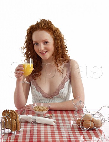 Young woman sitting at breakfast table Special K with milk wholemeal toast boiled eggs orange juice