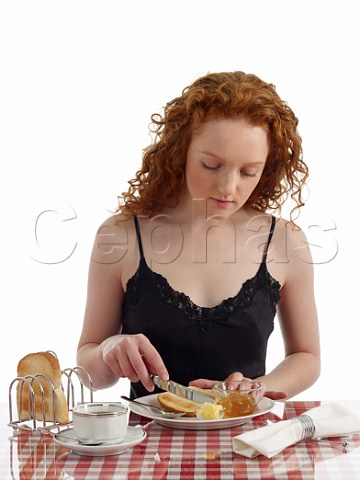 Young woman at breakfast table toast and marmalade cup of black coffee